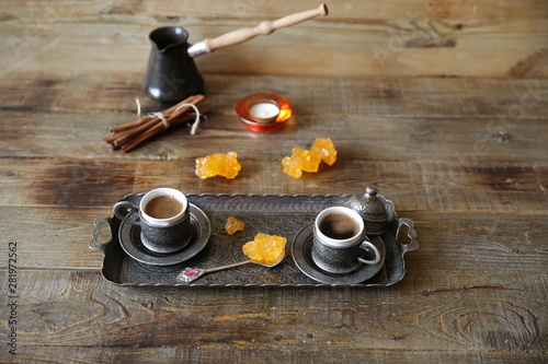turkish coffee in cups with vintage pattern with cezve and sweets on a wooden rustic table with copy space for text and image. Still life.