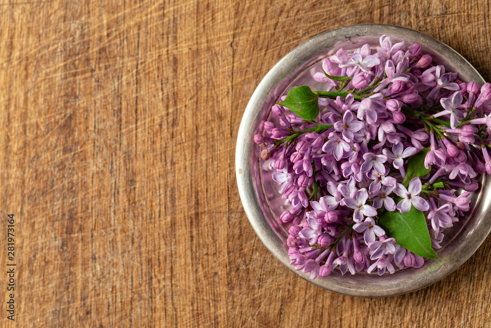 Lilac flowers on a silver plate on a wooden background