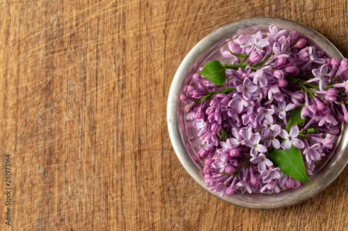 Lilac flowers on a silver plate on a wooden background
