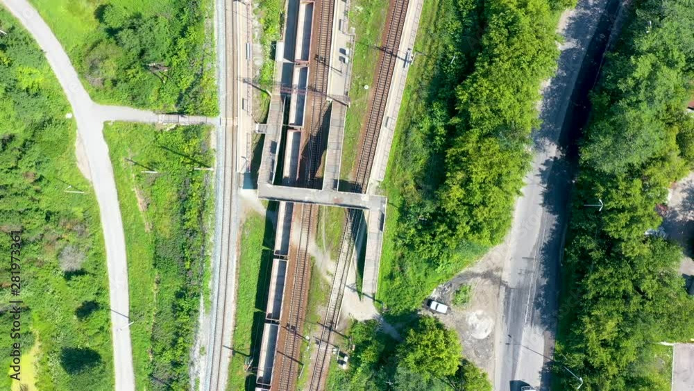 Top down aerial view of railway and train station surrounded by parks and fields with green grass and autumn color trees on a sunny day. Top down aerial view of railway and train station surrounded by parks and fields with green grass and autumn color trees on a sunny day.