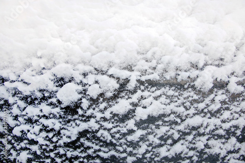 Background of white snowflakes on black glass, close-up