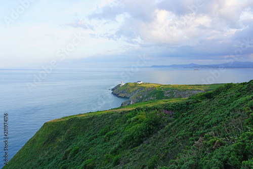 Photography View of green heather fields, the Baily Lighthouse and the Irish Sea seen from t