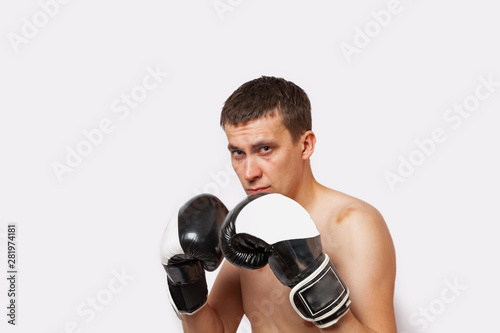 A man in boxing gloves with bruises on his body and face stands in a rack during a fight and boxing on a white isolated background