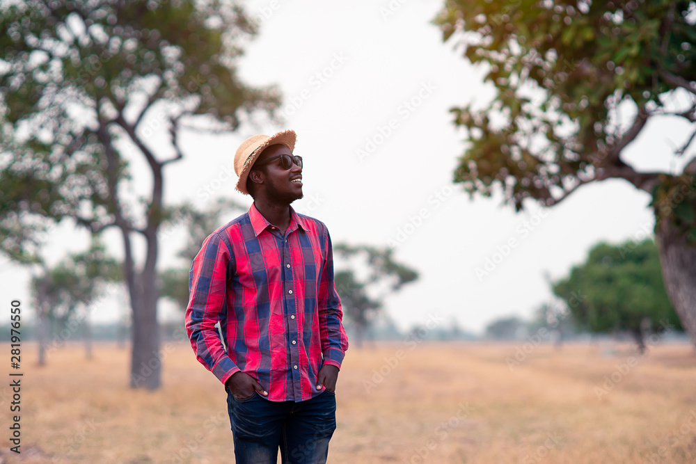 Portrait of african traveler smiling and enjoying his recreation time in nature.Concept of tourism day Portrait of african traveler smiling and enjoying his recreation time in nature.Concept of tourism day