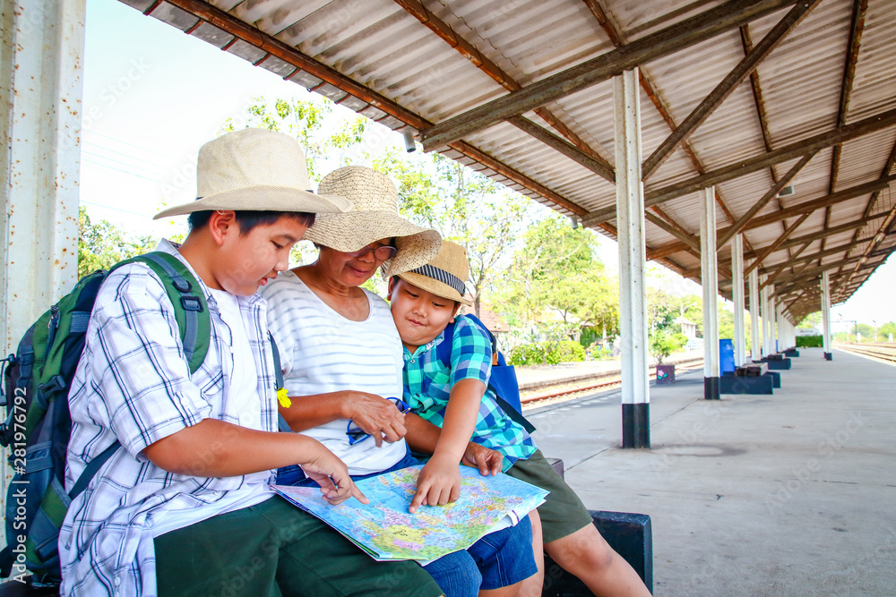 Grandmother and two nephews, see the map to travel At the train station in Thailand Grandmother and two nephews, see the map to travel At the train station in Thailand