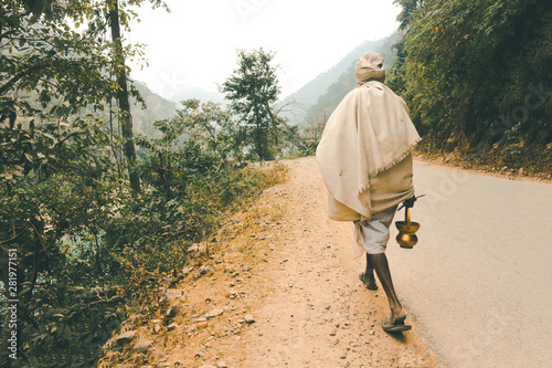 Indian renounced sadhu leaves on the way to the forest. A wandering wanderer with a trident and a kamandala. Photo from the back.