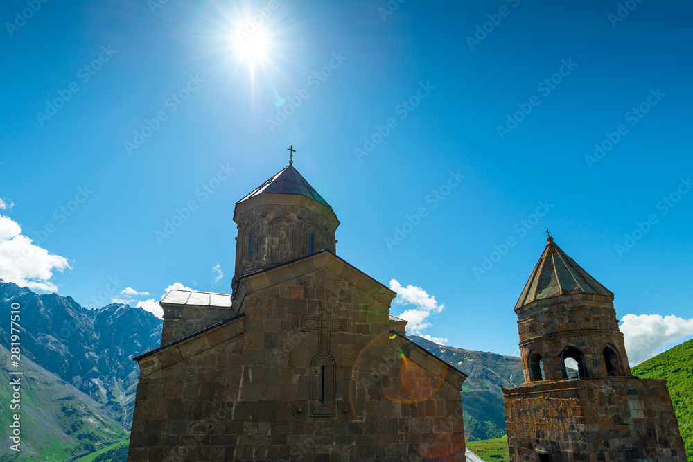 Georgia, view of the Trinity Church in the village of Gergeti on a background of mountains on a sunny day