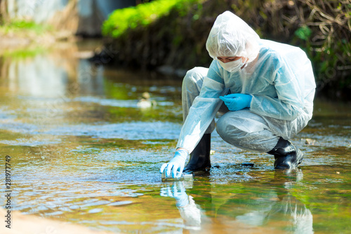 Fotografia scientist researcher in protective suit takes water for analysis from polluted r