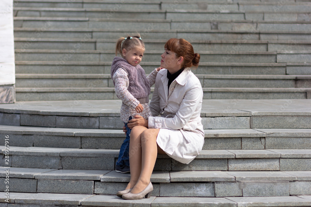 Child looking at mother with love on stairs outdoors