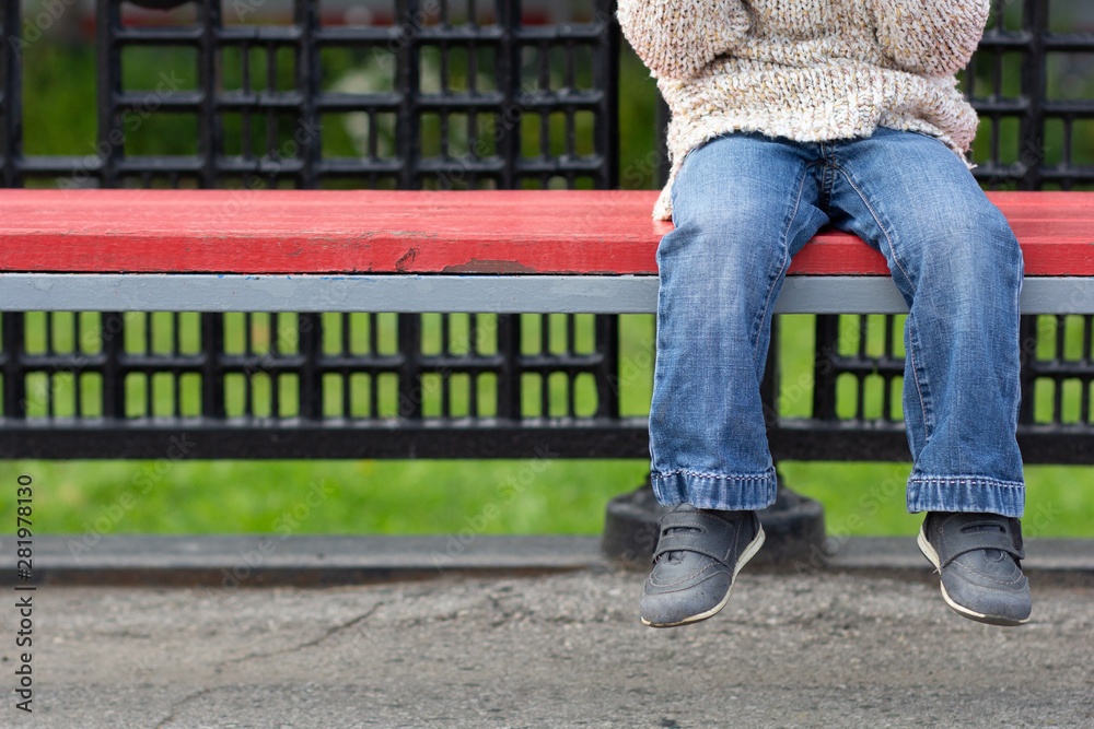 Фотография Child legs dangling from bench with copy space