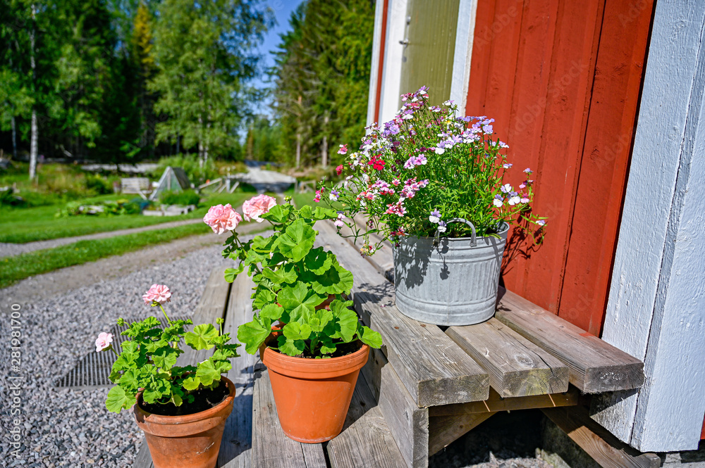 flowers on stairs infront of a red wooden cabin