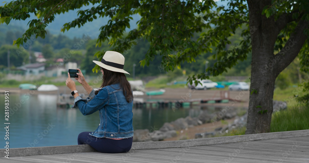 Woman take photo and sit on lake side