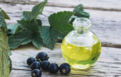 Fresh berries of black currant near glass bottles with extract. Medicinal tincture with black currant.