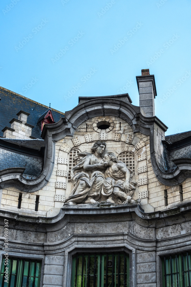 Gent, Flanders, Belgium -  June 21, 2019: Mammelokker beige stone fresco, daughter secretly breastfeeding jailed dad on side of Belfry, set in dark gray stone under blue sky.