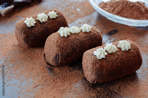 Delicious chocolate brownie as a potato form, Russian traditional dessert, on a dark desk and cacao powder on it, close up