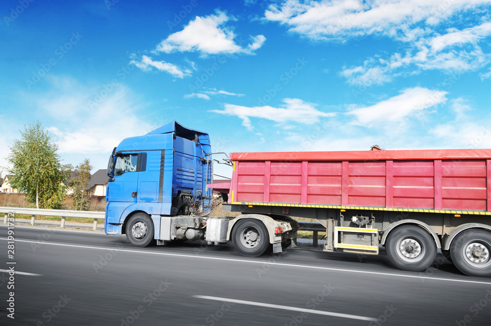 Truck with a trailer in motion on the countryside road against sky with clouds Truck with a trailer in motion on the countryside road against sky with clouds