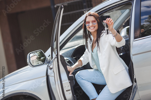 Young attractive woman just bought a new car. female holding keys from new automobile. photo