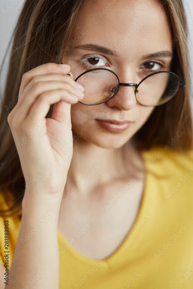 beautiful attractive girl in round glasses looking at the camera. fashion and style concept. people, optic. close up portrait beautiful attractive girl in round glasses looking at the camera. fashion and style concept. people, optic. close up portrait