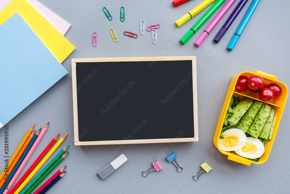 School supplies and lunch box with sandwich and vegetables. Back to school. Healthy eating habits concept - background layout with free text space. Flat lay composition, mockup, top view School supplies and lunch box with sandwich and vegetables. Back to school. Healthy eating habits concept - background layout with free text space. Flat lay composition, mockup, top view