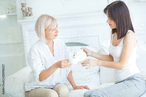 two women talking. Mother and daughter indoors together.Ladies drinking tea. Two females at home. Mature mother and her adult daughter embracing.