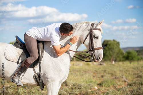 Cheerful man riding and hugging horse