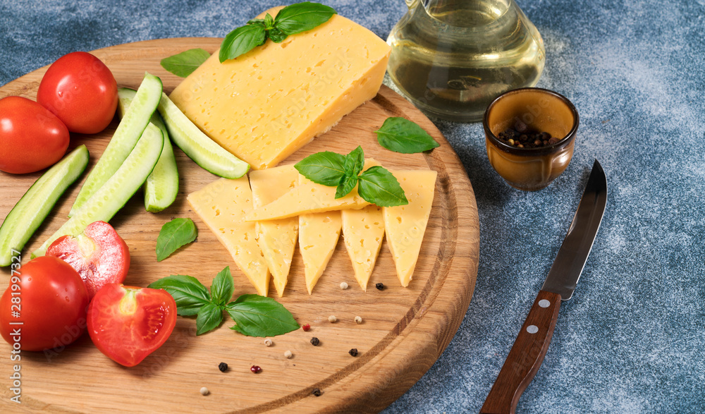 Dutch cheese with cucumbers and tomatoes and basil on a blue background. Dutch cheese with cucumbers and tomatoes and basil on a blue background.