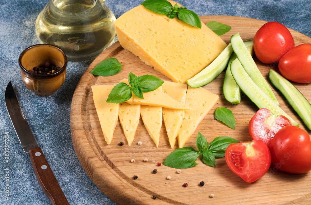 Dutch cheese with cucumbers and tomatoes and basil on a blue background. Dutch cheese with cucumbers and tomatoes and basil on a blue background.