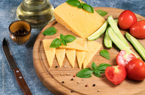 Dutch cheese with cucumbers and tomatoes and basil on a blue background.