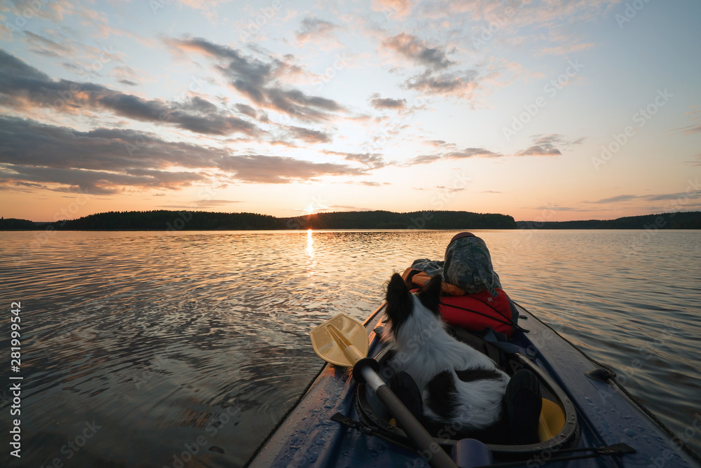 The hostess and the dog are sailing on the lake in a kayak boat at sunset . The hostess and the dog are sailing on the lake in a kayak boat at sunset .