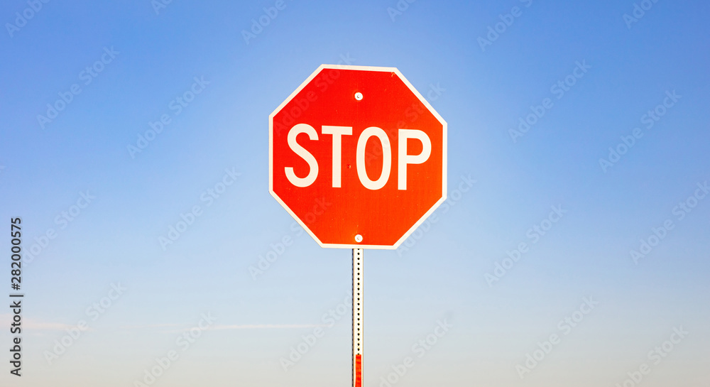 Stop sign against blue sky background. Sunny spring day - obrazy, fototapety, plakaty 