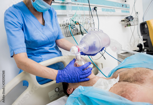 Doctors give resuscitation to a male patient in the emergency room. Cardiac massage photo