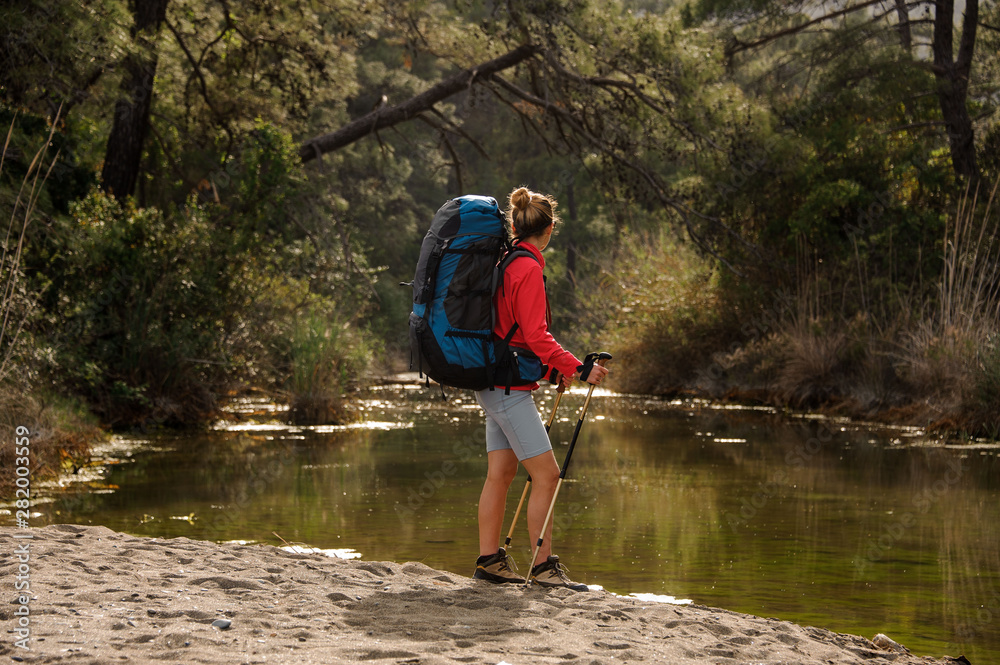 Female traveller standing by forest river shore Female traveller standing by forest river shore