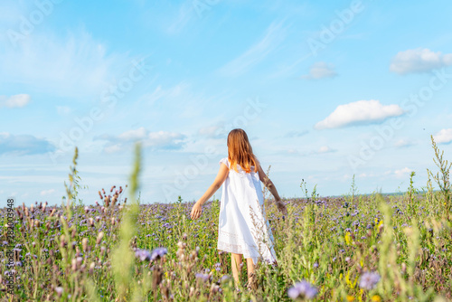 girl in a field of buckwheat. girl in white dress from back. girl in the harvest field