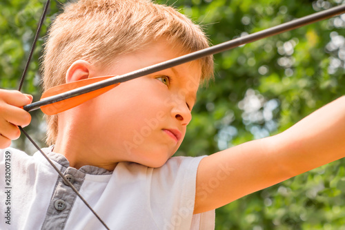 Archery school. Boy with a bow and arrow. Children and sports. Archery background. Junior archery championship. Archery for kids