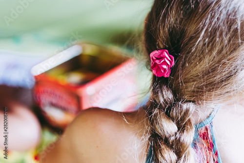 Coiffure enfant tresse et petite fleur rose