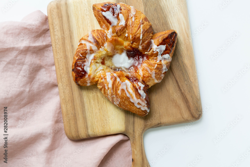 Strawberry and Sweet Cheese Danish with Icing Drizzle on Wooden Serving Board, Pink Napkin, Fruit Pastry Flat Lay on White Background Strawberry and Sweet Cheese Danish with Icing Drizzle on Wooden Serving Board, Pink Napkin, Fruit Pastry Flat Lay on White Background