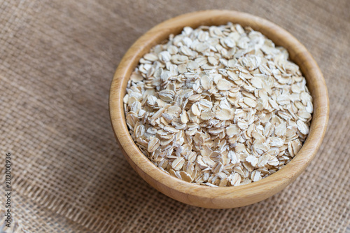 Uncooked oatmeal or oat flakes in a wooden bowl