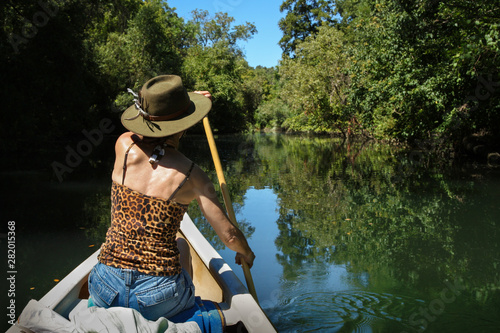 Woman in leopard tee-shirt canoeing in lush river photo