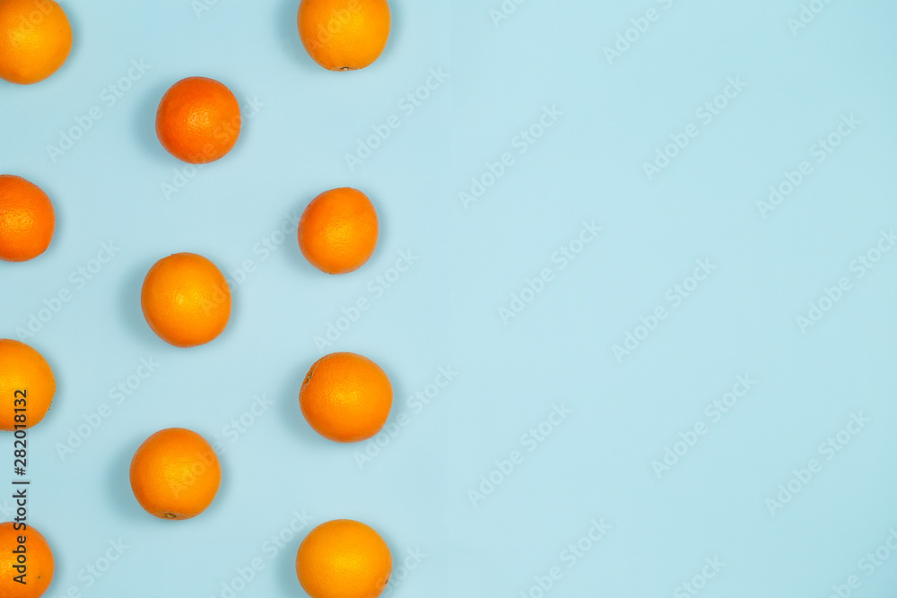 Oranges fruits pattern with oranges over a light blue background with large copy space.