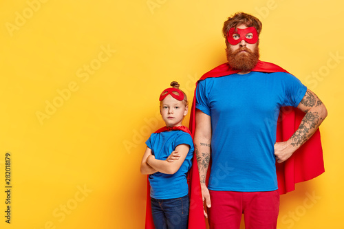 Obraz na płótnie Photo of serious bearded man and self confident little child stands near with cr