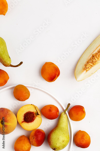 Fototapeta Naklejka Na Ścianę i Meble -  Sliced ripe juicy melon, apricots and pears on a white background. Top view.