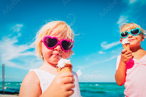 happy cute little girls eating ice cream on beach