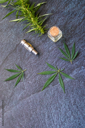Fototapeta Naklejka Na Ścianę i Meble -  Close-up Vaping Cannabis THC Oil Extract in Cartridge Isolated on Dark Background with Marijuana