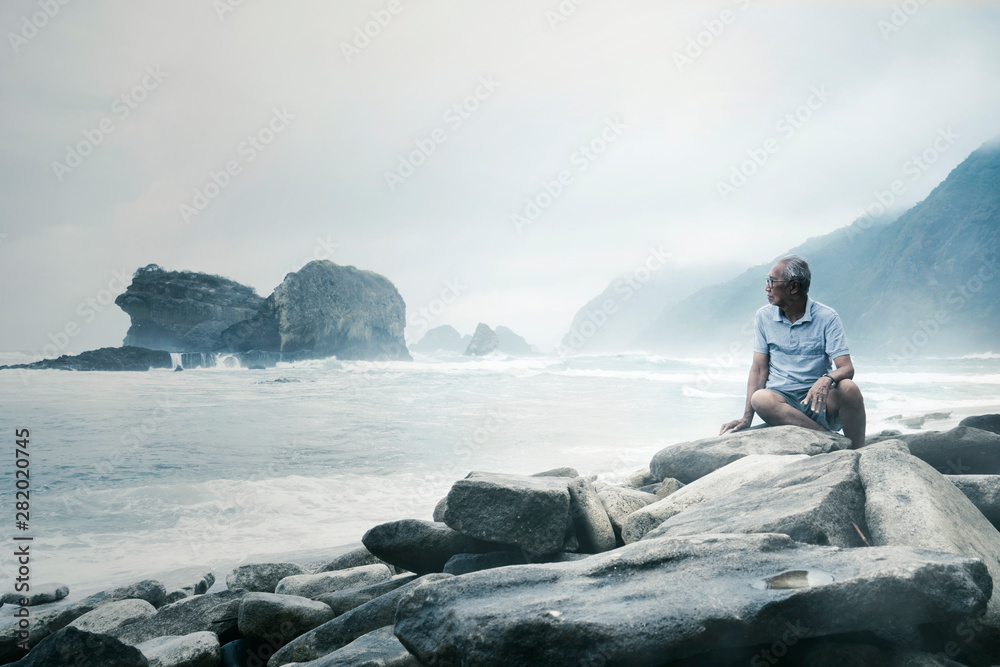 Elderly man enjoying a foggy Papuma beach view Elderly man enjoying a foggy Papuma beach view