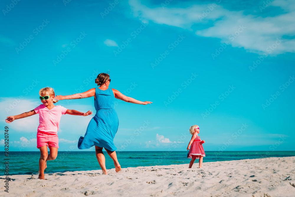 happy mother with little daughters play on beach