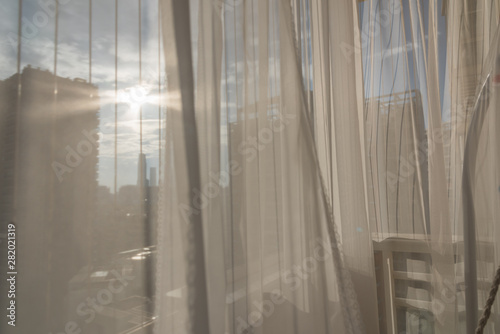 Looking at modern architectural light and shadow through translucent white gauze curtains on the balcony