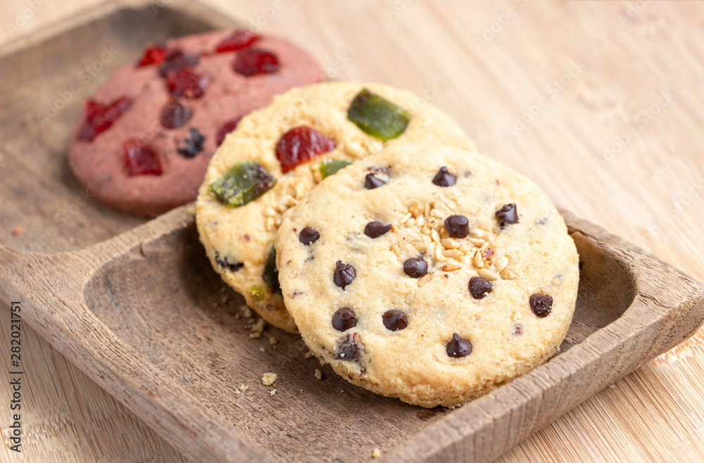 Chocolate chip cookie and mixed fruits cookie with wooden tray on the wood table. Delicious homemade baked cookie.