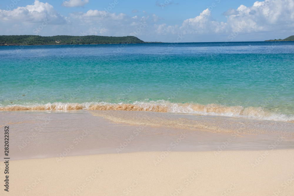 Tropical sandy beach in caribbean with an island on the horizon.