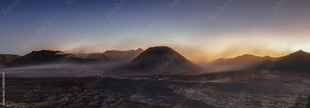 Mount Bromo sunset panorama with fog and smoke covering the mountains flow. 