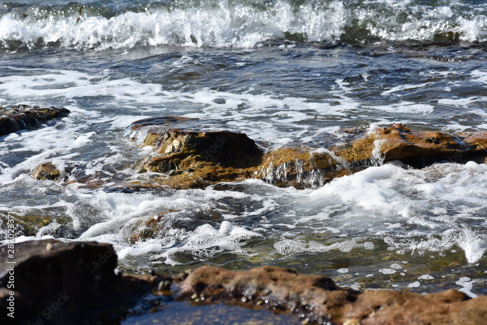 Sea water wave against rocks